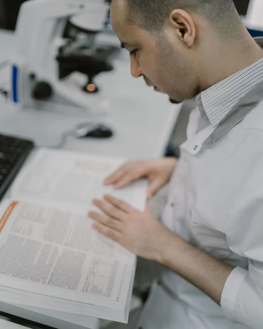 A researcher in a laboratory reading a printed journal issue